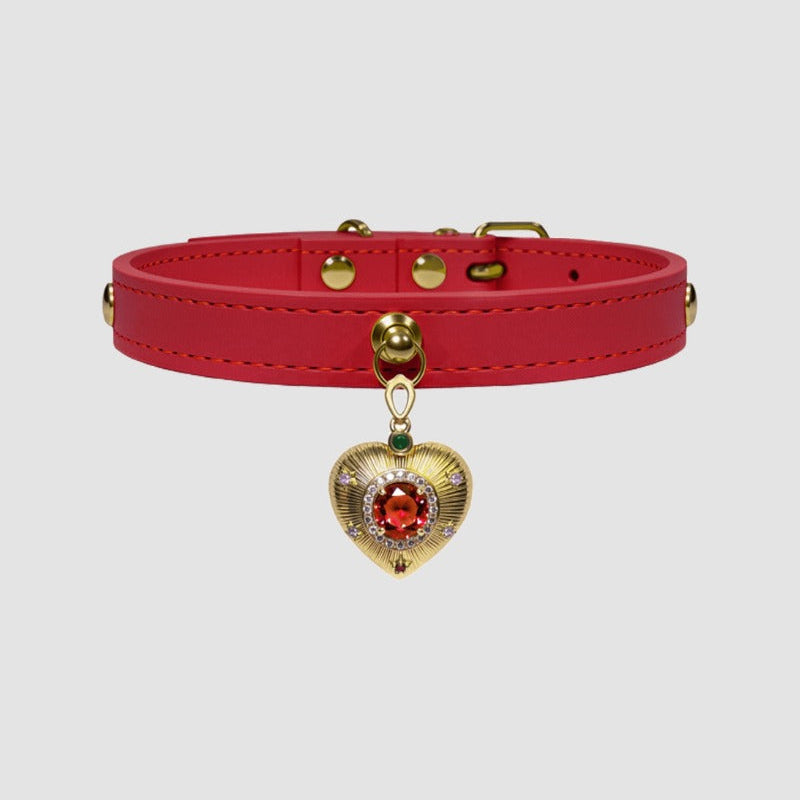 Red leather choker with a gold heart-shaped pendant featuring a red gemstone on a light gray background.