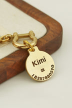 Gold tag with engraved name and numbers on a wooden surface