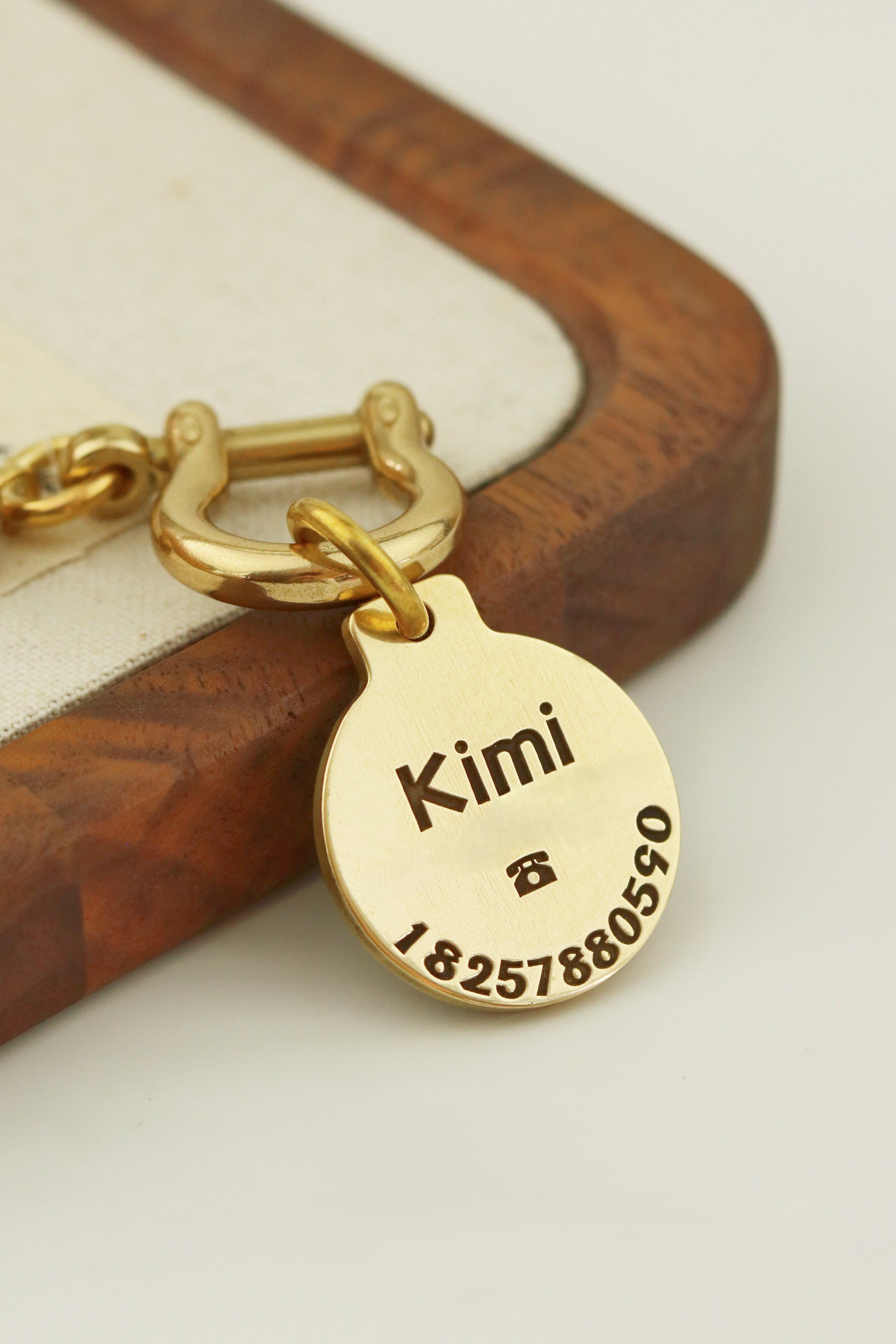 Gold tag with engraved name and numbers on a wooden surface
