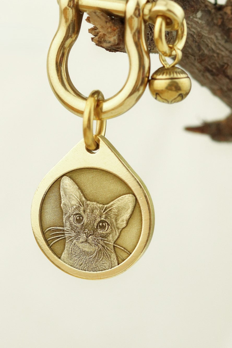 Gold keychain with a cat pendant on a neutral background