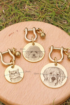 Gold dog tags with engraved pet portraits on a wooden surface with grass in the background.