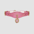 Pink dog collar with a decorative charm on a light gray background