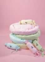 Stack of pastel-colored cushions with decorative elements on a pink background