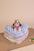 Small dog sitting on a layered pet bed with a checkered pattern against a beige background