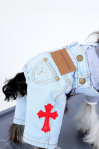 Dog wearing a denim outfit with a red cross patch on a white background